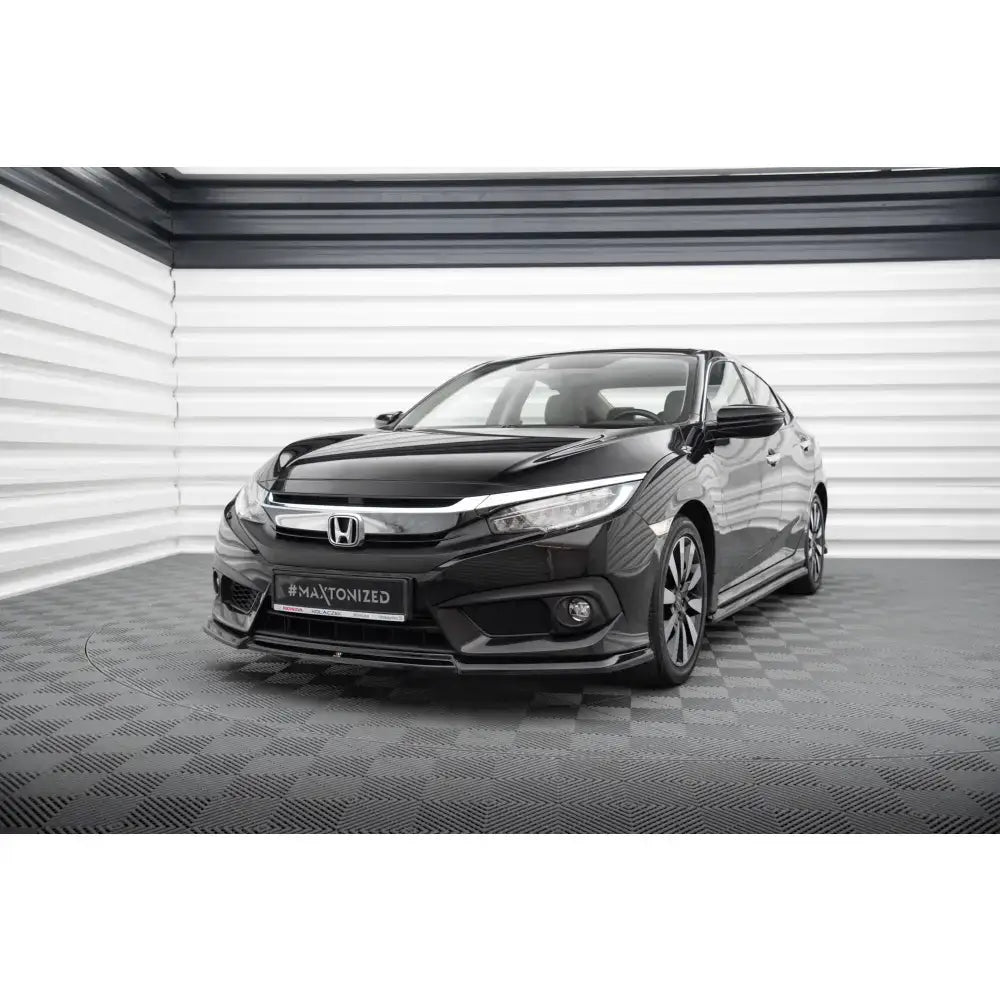 Frontsplitter på Honda Civic Mk10 med kromdetaljer og moderne lykter, sett skrått forfra i lyst rom.