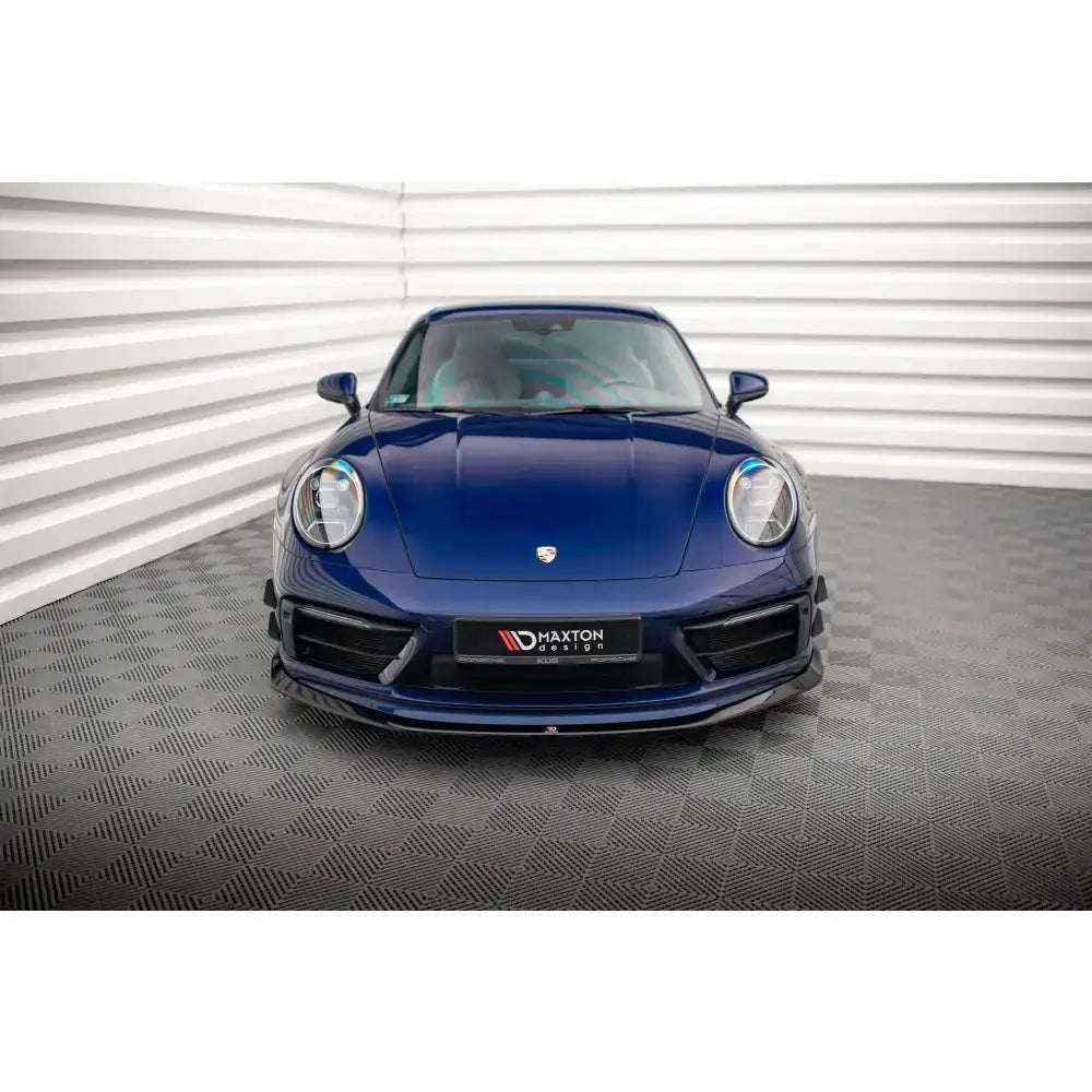 Frontspoiler på Porsche 911 Carrera Aero 992, mørkeblå bil sett forfra med tydelig emblem.