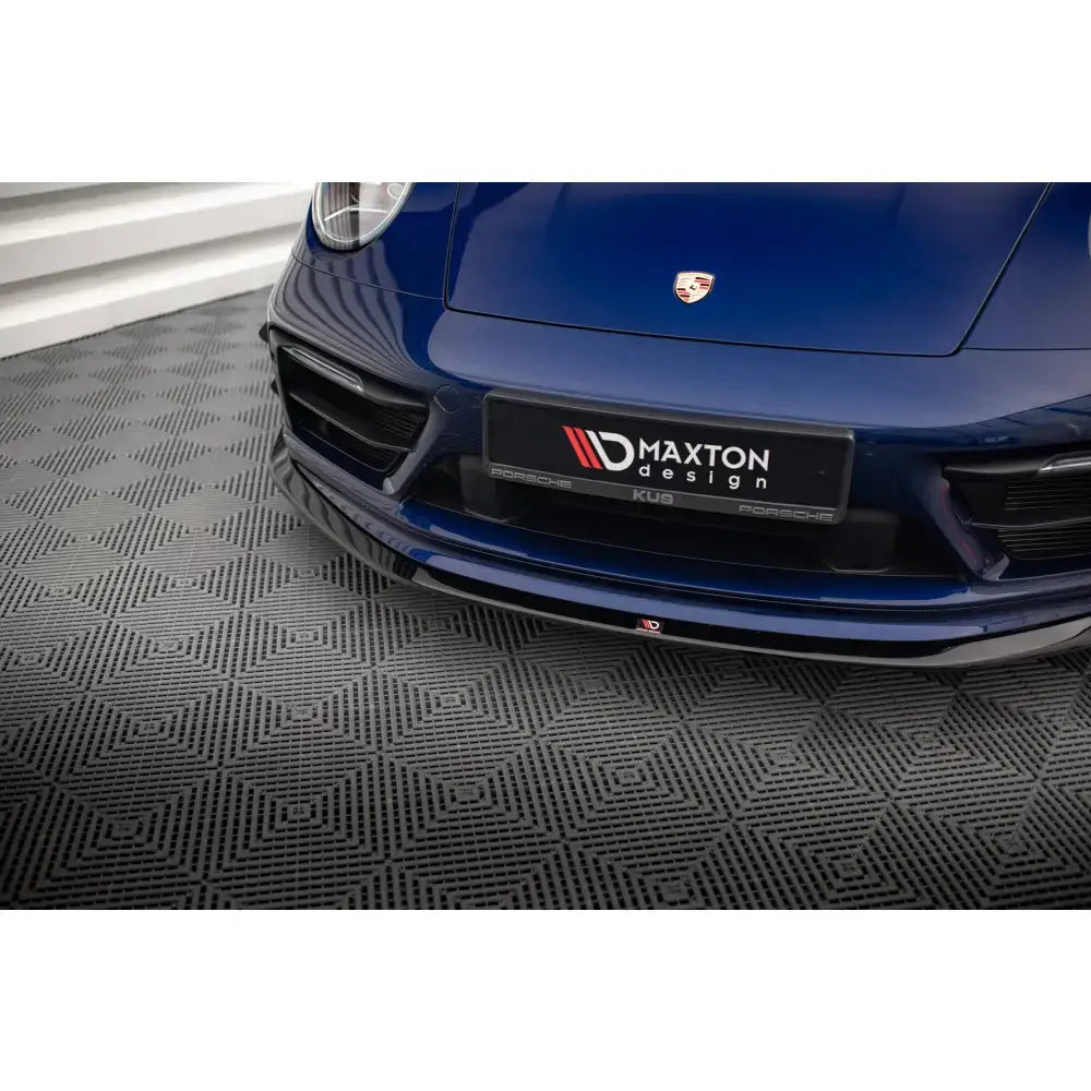 Front splitter på Porsche 911 Carrera Aero 992, blå bil med sort splitter på grått mønstret gulv.