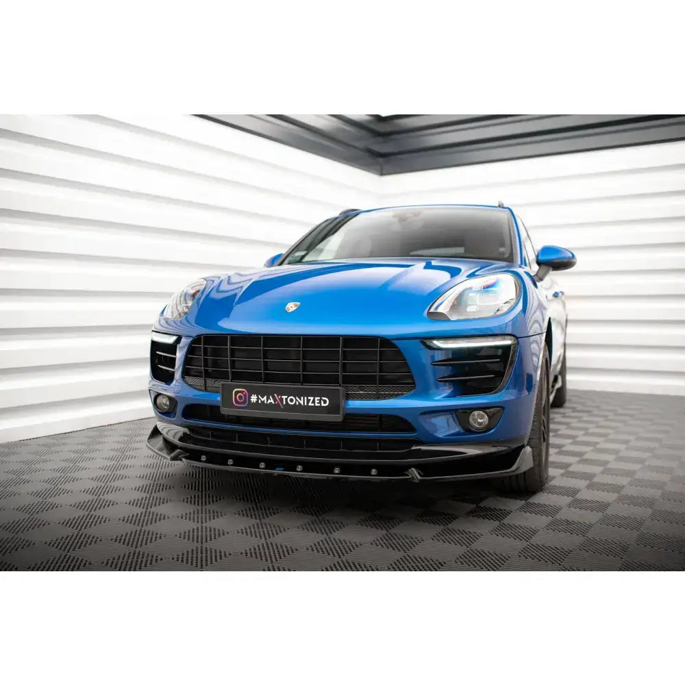 Frontsplitter på blå Porsche Macan Mk1 sett forfra med svart frontspoiler i lyst rom.