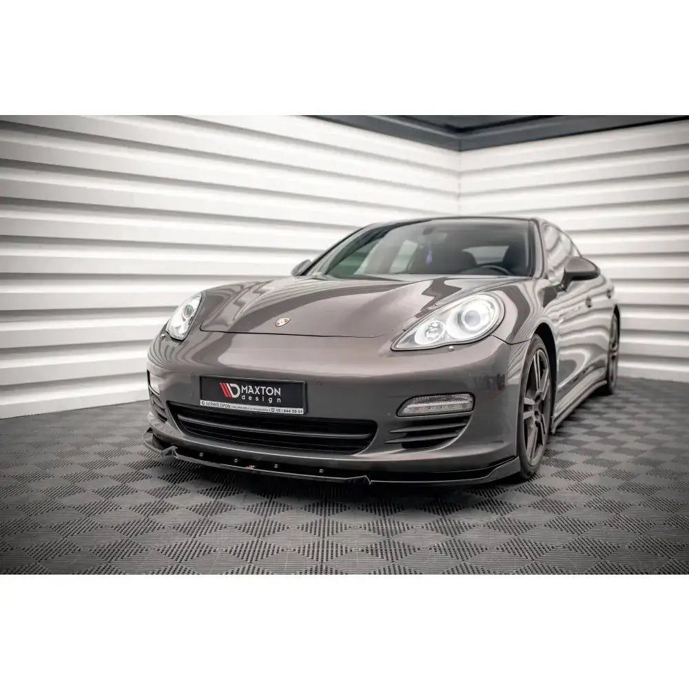 Frontsplitter på Porsche Panamera 970 med sorte felger, sett skrått forfra innendørs.