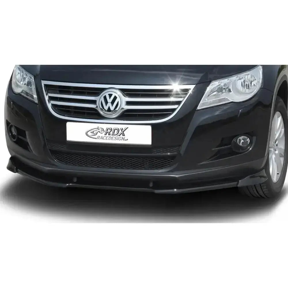 Frontleppe Volkswagen Tiguan 07-11 i sort plast montert på frontfanger, nærbilde med grill og lykter.