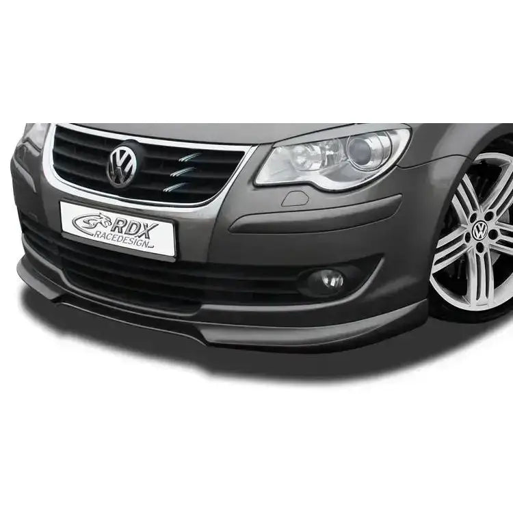 Frontleppe Volkswagen Touran 07-10 montert på grå bil, synlig grill, frontlykt og felg med VW-logo.
