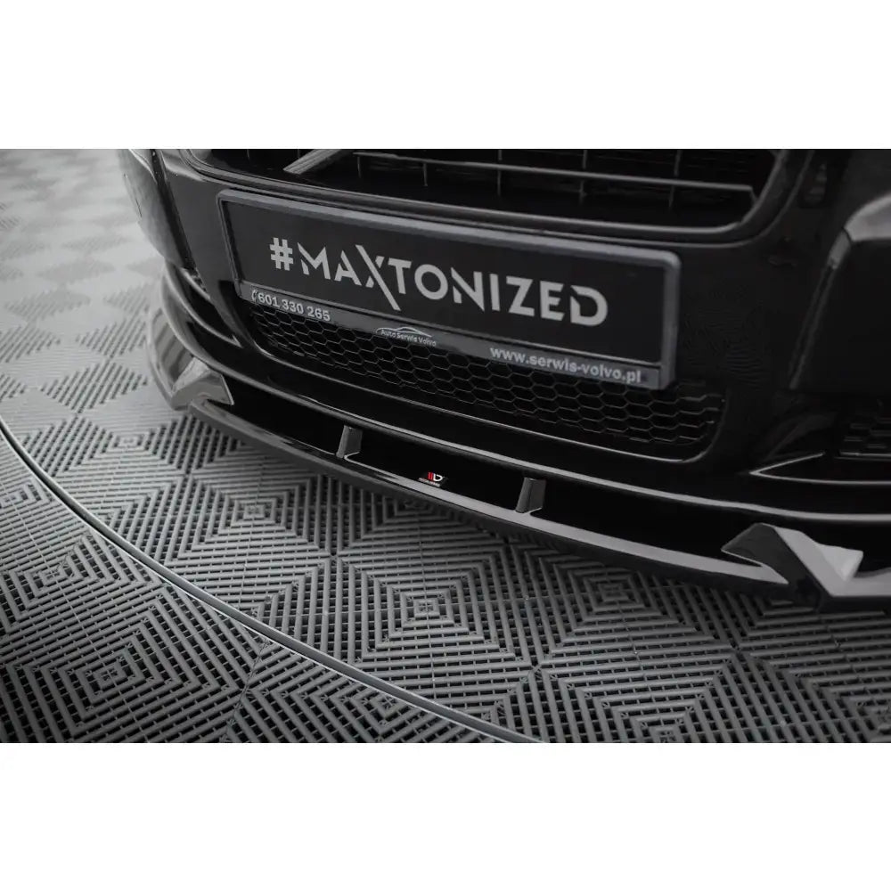 Frontsplitter til Volvo S80 Mk2 i sort blank finish med aerodynamiske detaljer, sett forfra fra lav vinkel.
