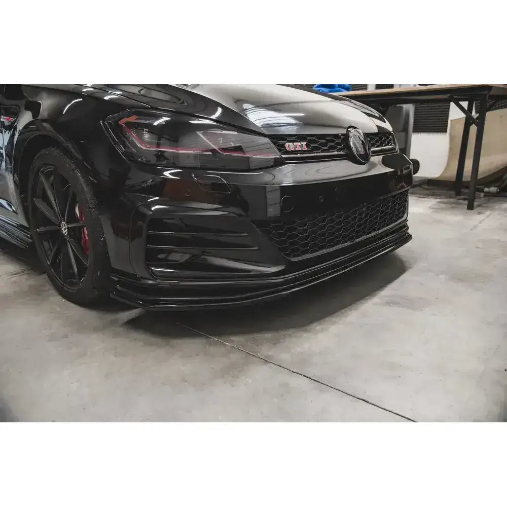 Front lip på VW Golf 7 GTI TCR med sort frontspoiler, røde bremsekalipere og GTI-emblem.