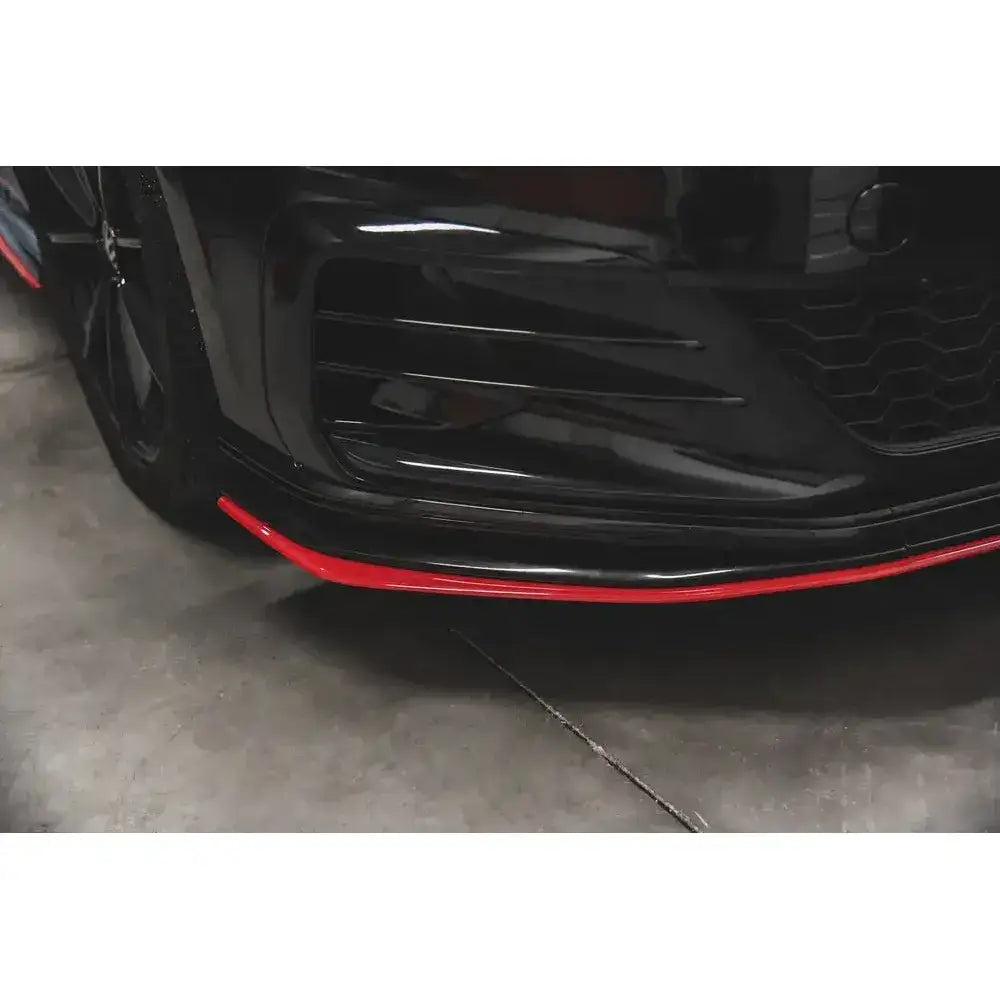 Frontsplitter til Vw Golf 7 GTI TCR i sort med rød kant, sett fra skrå vinkel nær bakken.