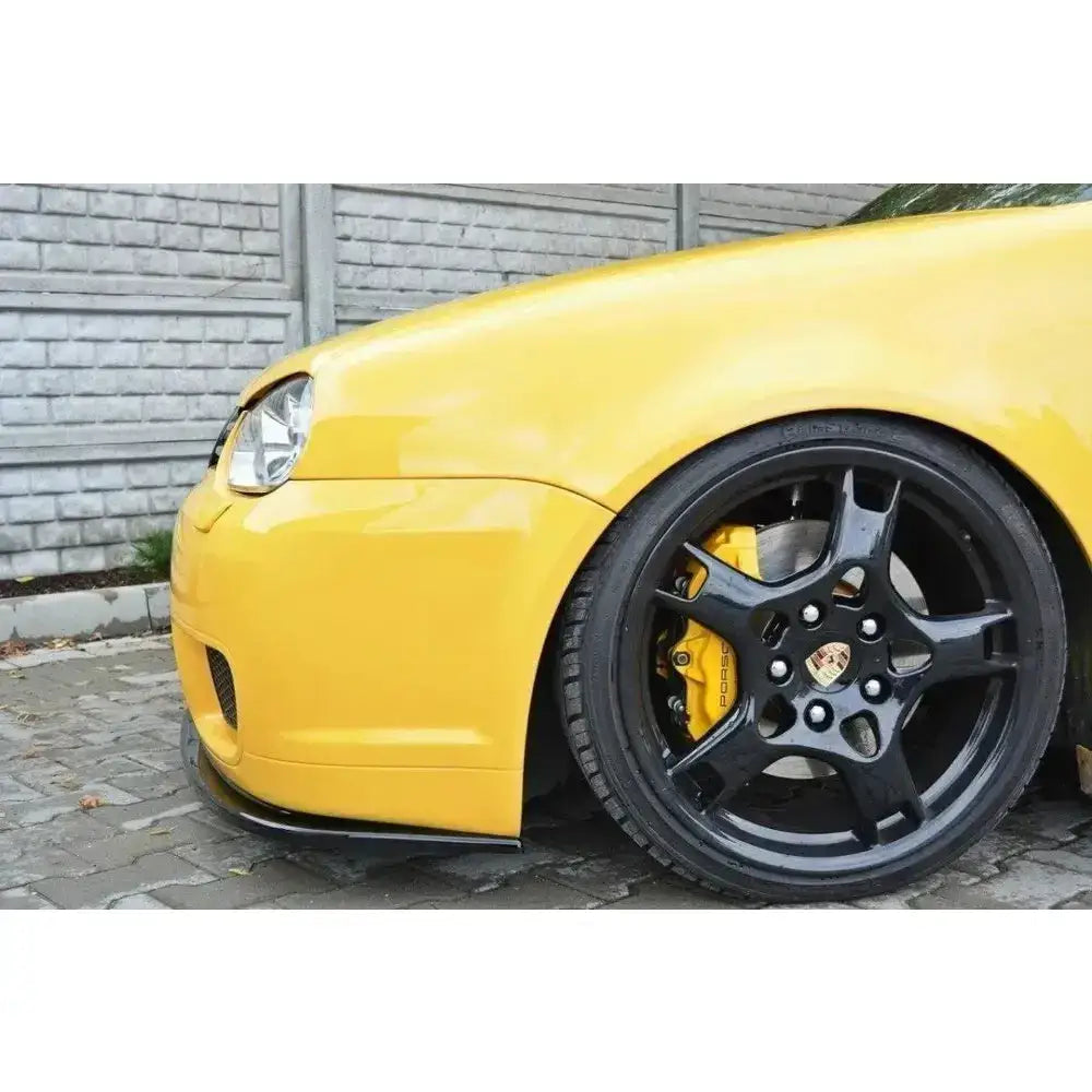 Front splitter på gul VW Golf IV R32 med svarte Porsche-felger og gule bremsekalipere på brostein.