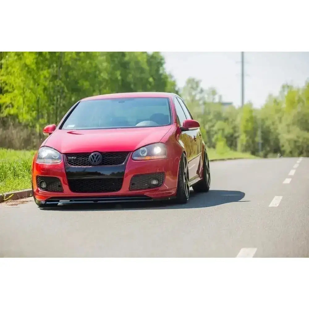 Frontsplitter til VW Golf V GTI montert foran på rød bil med sorte detaljer, sett forfra på vei.