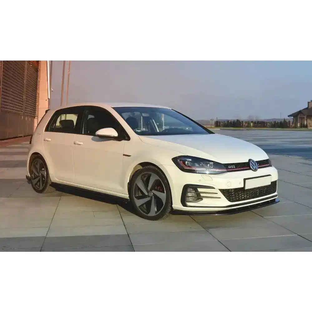 Frontsplitter på VW Golf VII GTI Facelift V.1 med sorte felger og rød stripe, parkert utendørs.