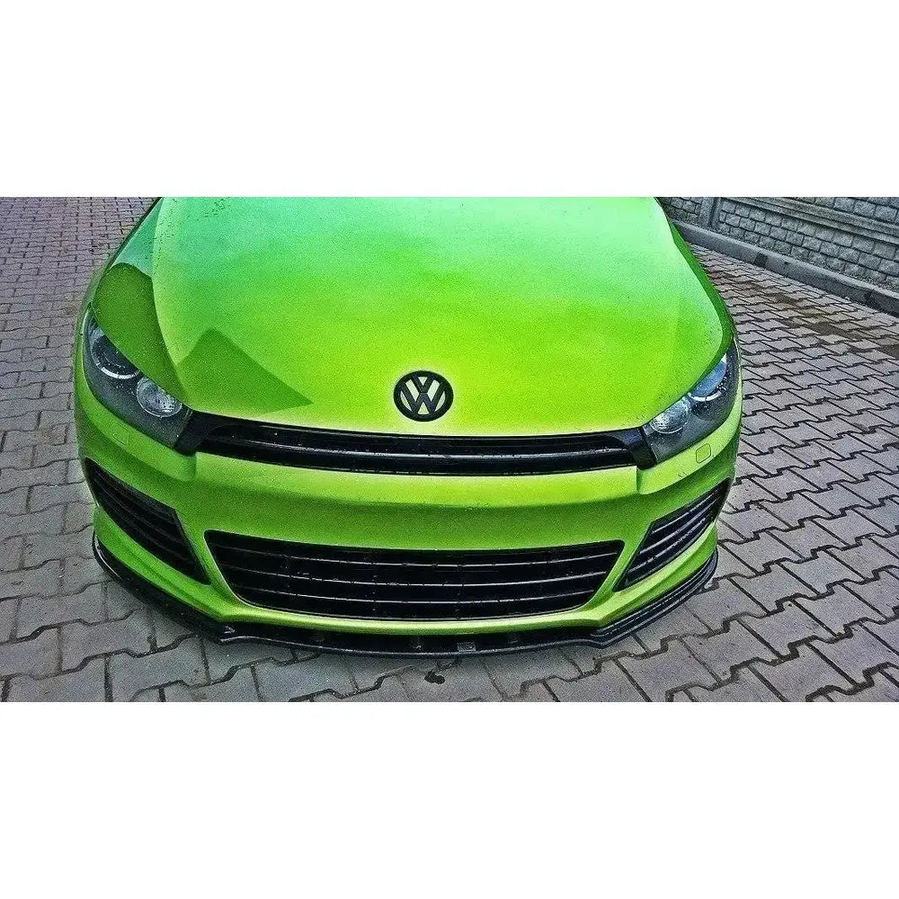 Frontsplitter til VW Scirocco R vist på grønn bil med sorte detaljer og Volkswagen-emblem.