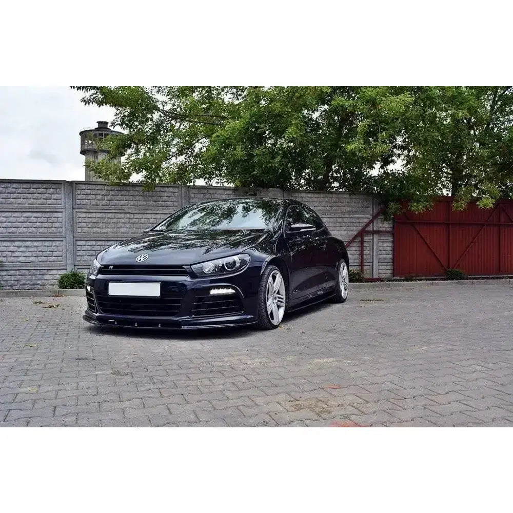 Frontleppe på VW Scirocco R med blank sort finish, lave sideskjørt og sølvfelger utendørs.