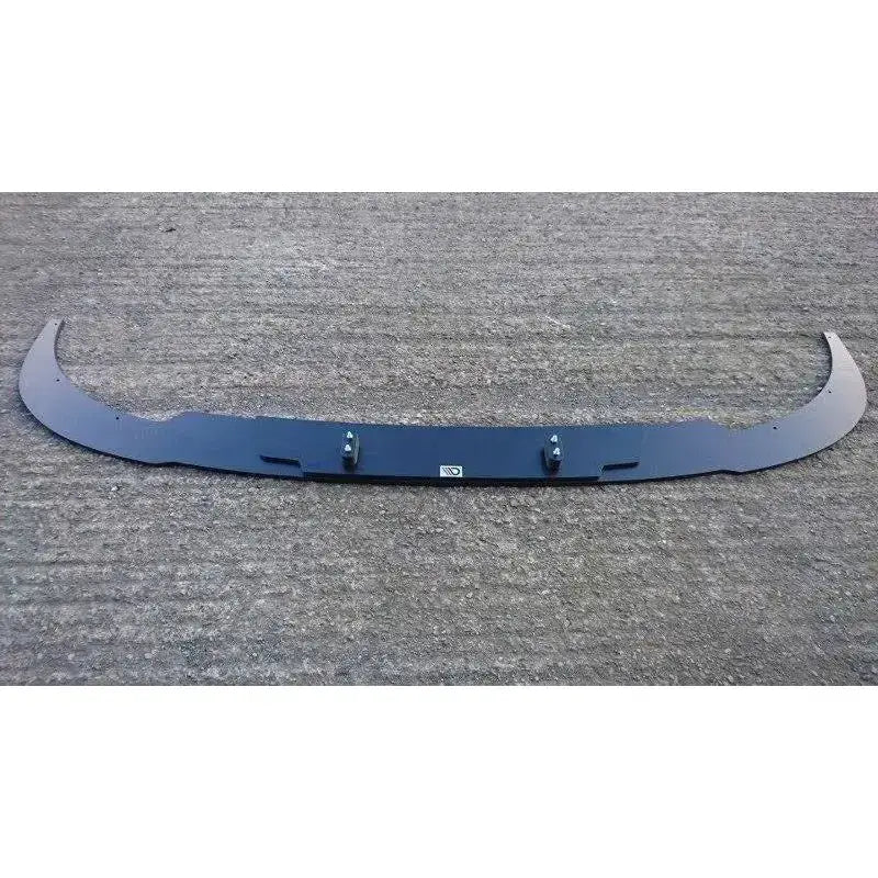 Front splitter til VW T5 Sportline, svart med logo og festebolter, fotografert ovenfra på grå betong.