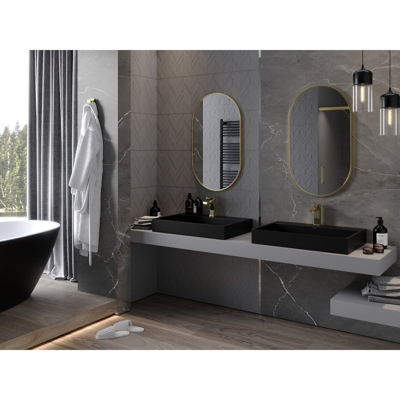 Speil baderom ovalt med gull ramme over svarte rektangulære vasker og grå benkeplate.