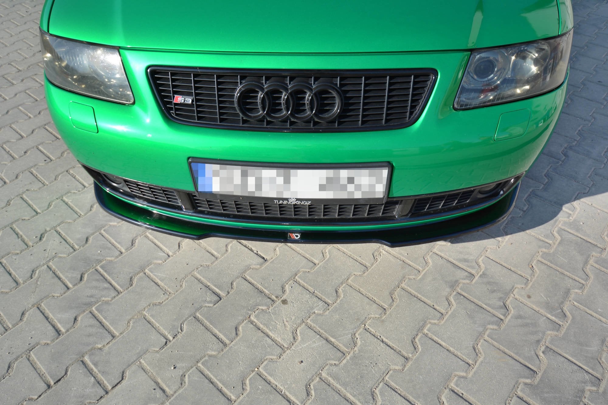 Frontleppe Audi S3 8L RS montert på grønn bil med svart grill og emblemer, sett skrått ovenfra.