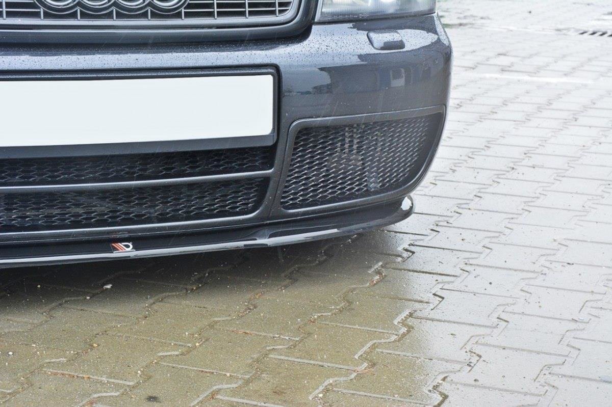 Spoiler til Audi S4 B5 med sort gitter og logo, sett forfra på våt belegningsstein.