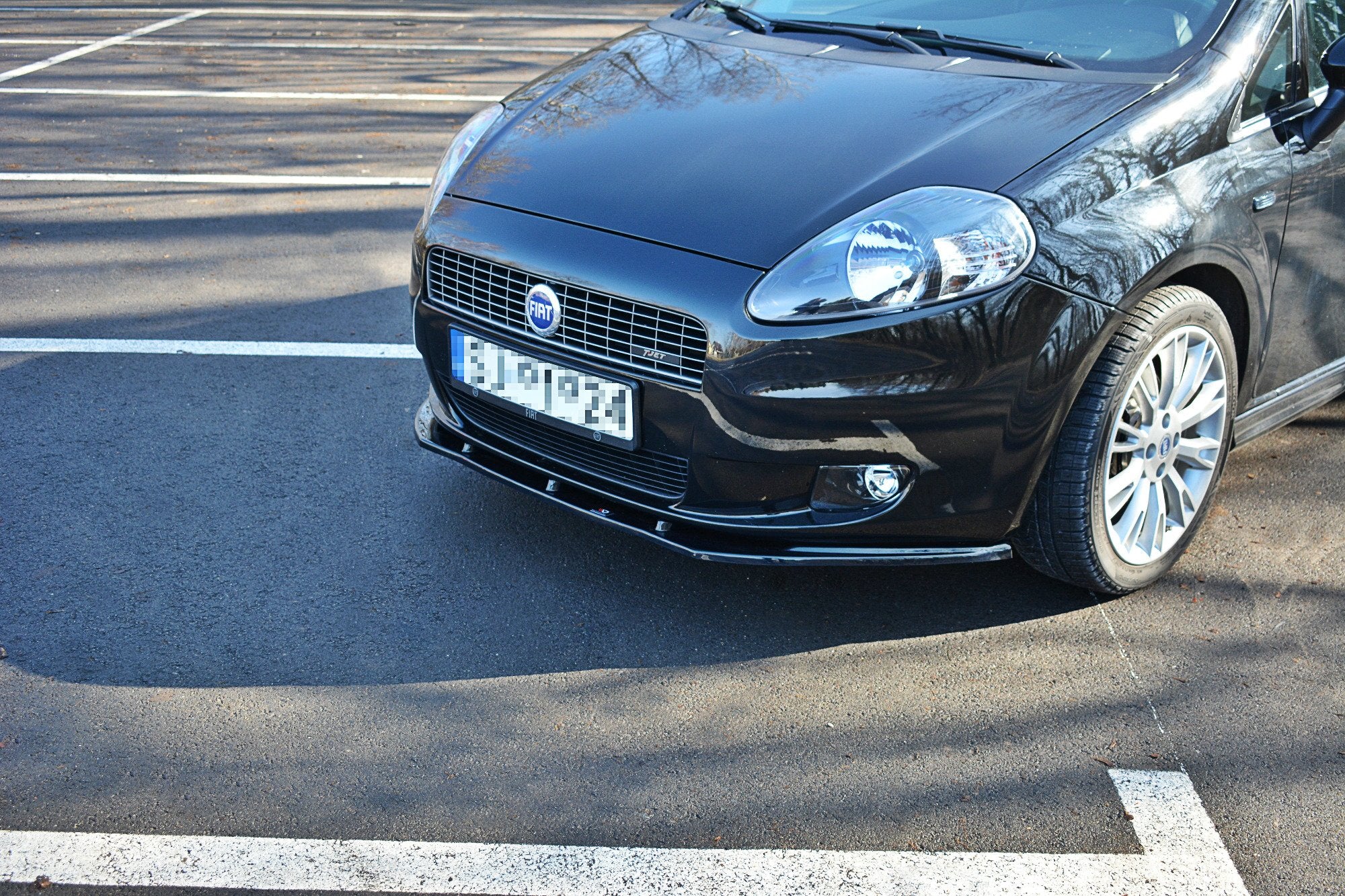 Frontleppe på Fiat Grande Punto standard, sort bil med sølvfelger og tåkelys sett skrått forfra.