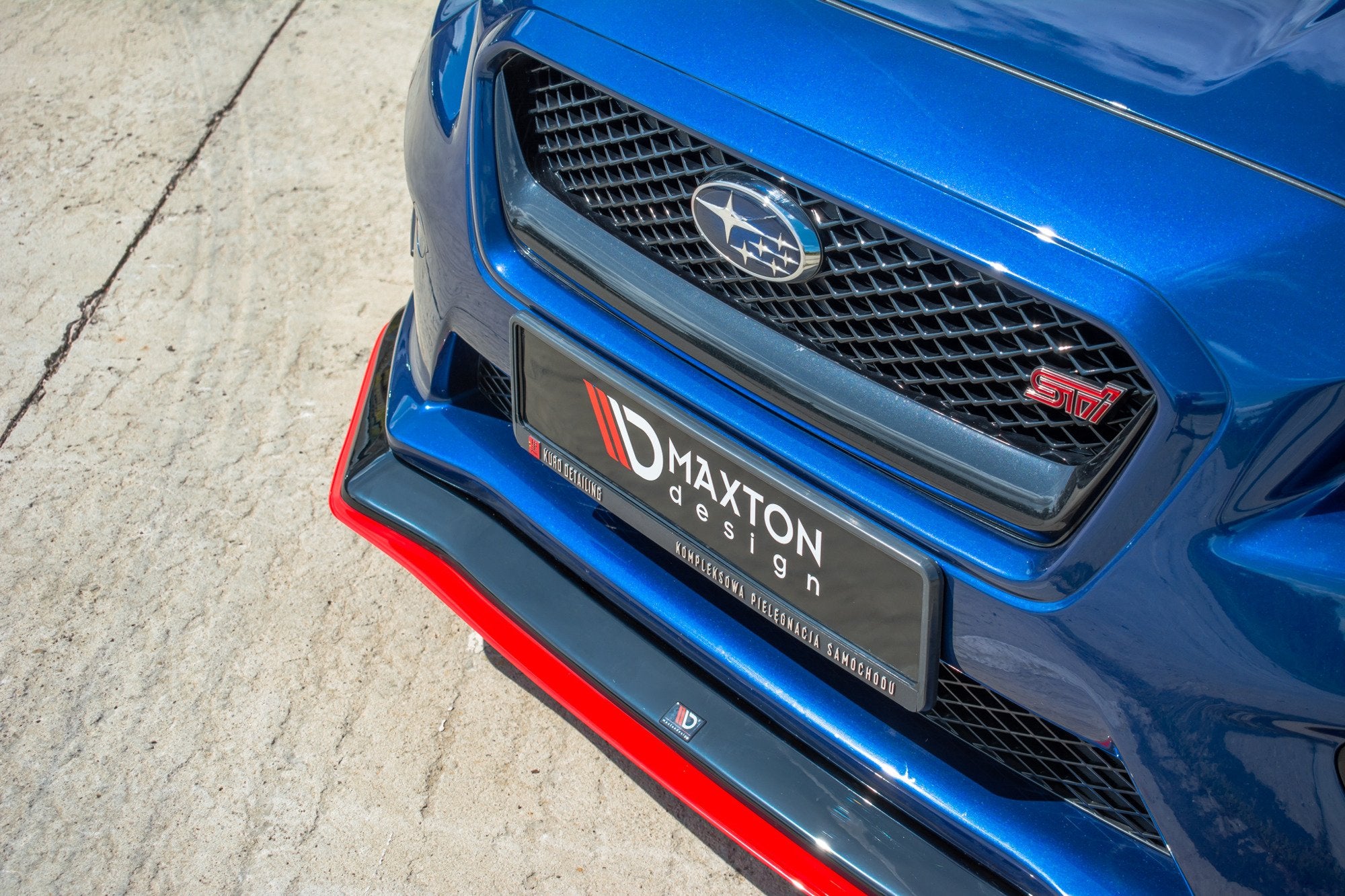 Frontleppe Subaru WRX Sti ABS V.3 montert på blå bil med rød STI-logo og sort grill, sett forfra.