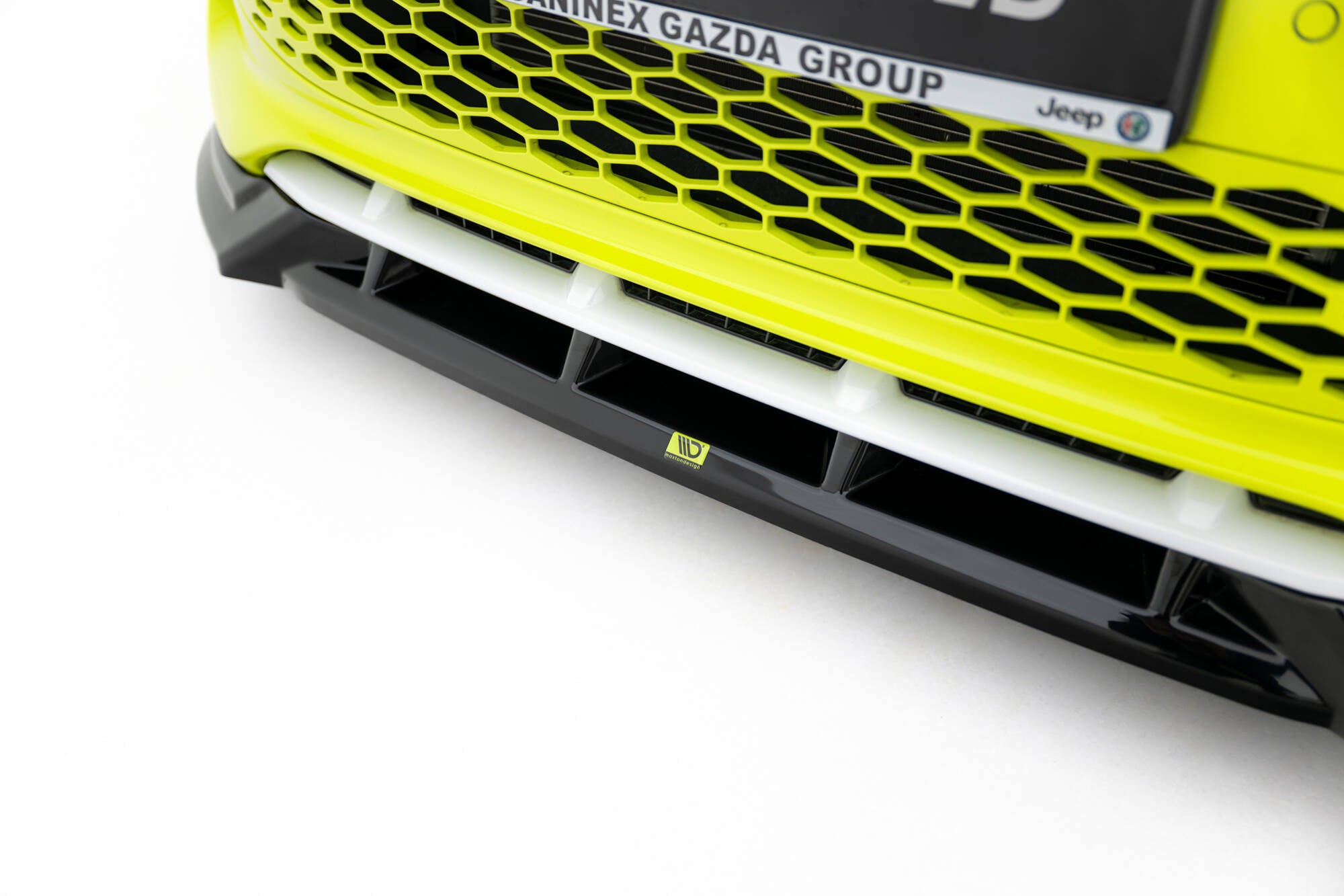 Spoiler på Abarth 500E i hvitt under limegrønn bilfront med sort bikubemønstret grill.