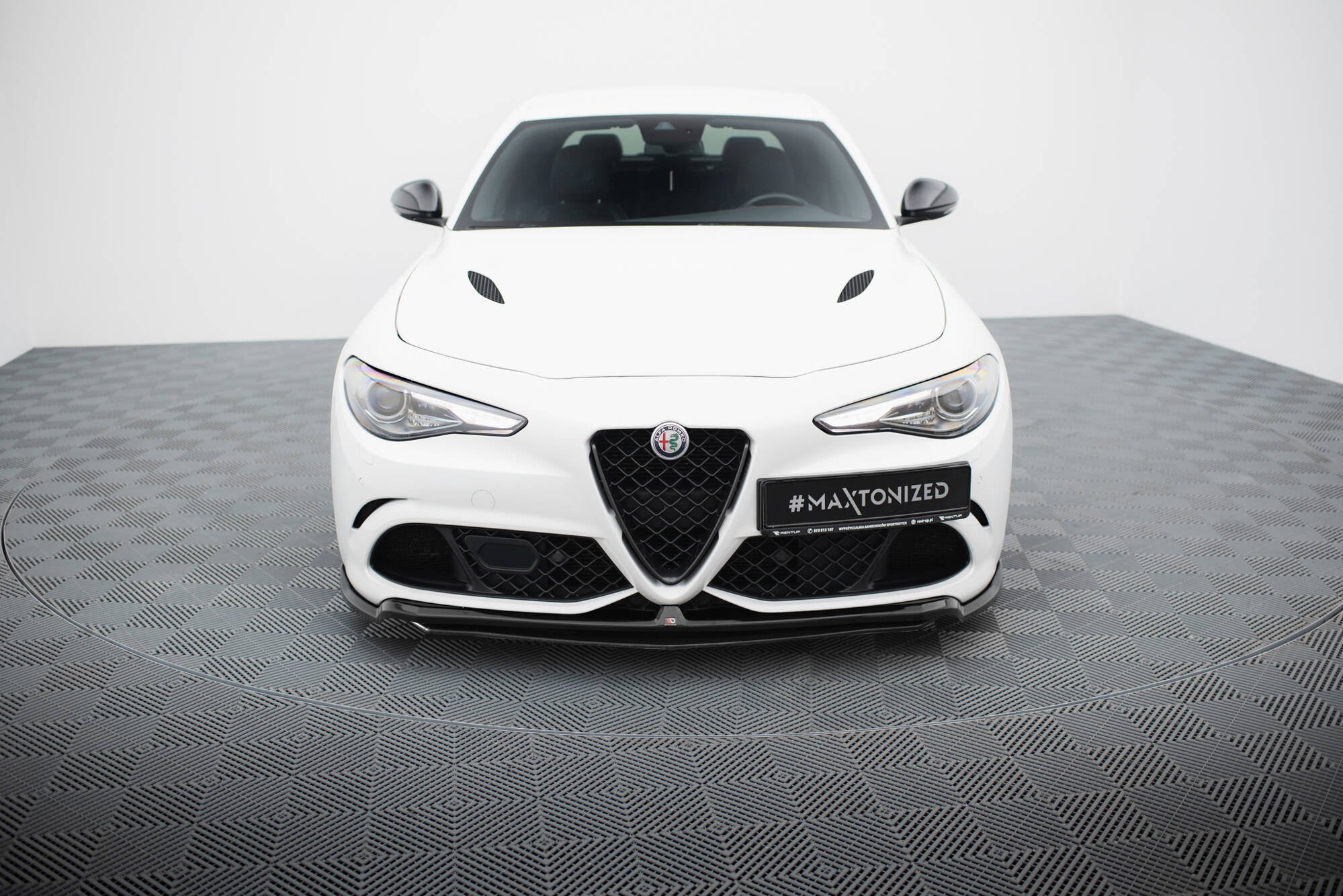 Front splitter på hvit Alfa Romeo Giulia Quadrifoglio med svart grill og markante luftinntak foran.