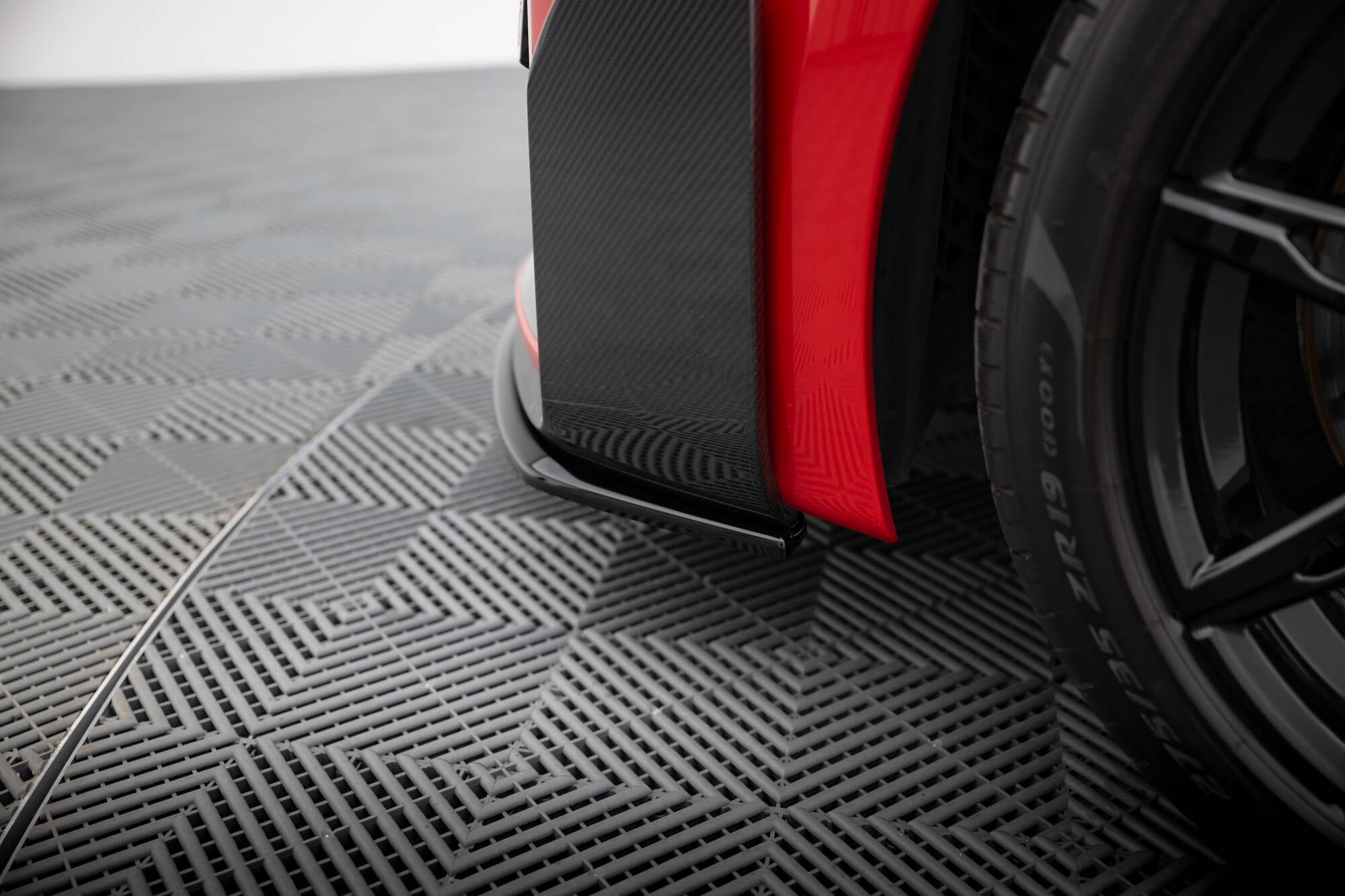 Spoiler på BMW M2 M-Performance G87 i rød og sort karbonfiber ved siden av svart dekk.