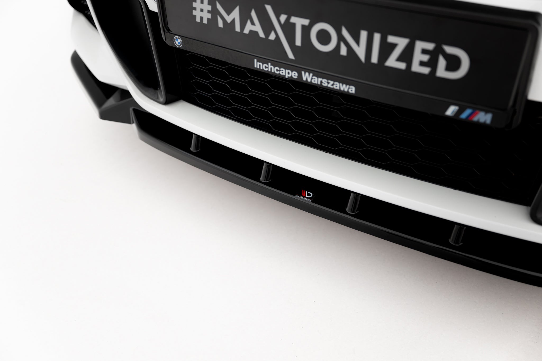 Spoiler til BMW X1 M-Pakke F48 Facelift i sort blank plast med Maxton Design-logo, sett forfra skrått.