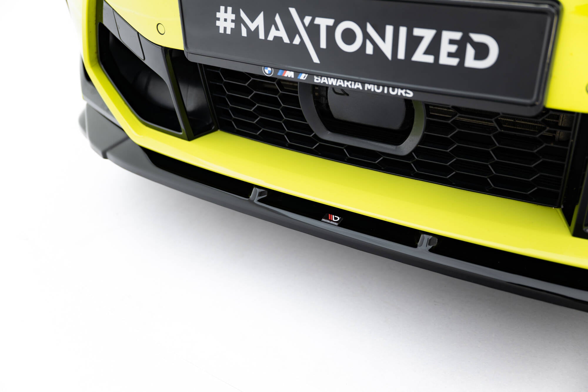 Spoiler på BMW X4M F98 Facelift i blank sort plast med liten logo og gulgrønn støtfanger.