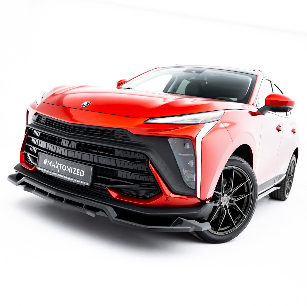 Frontspoiler på rød Forthing T-Five MK1 SUV med sort grill, LED-lys og sorte alufelger i fotostudio.