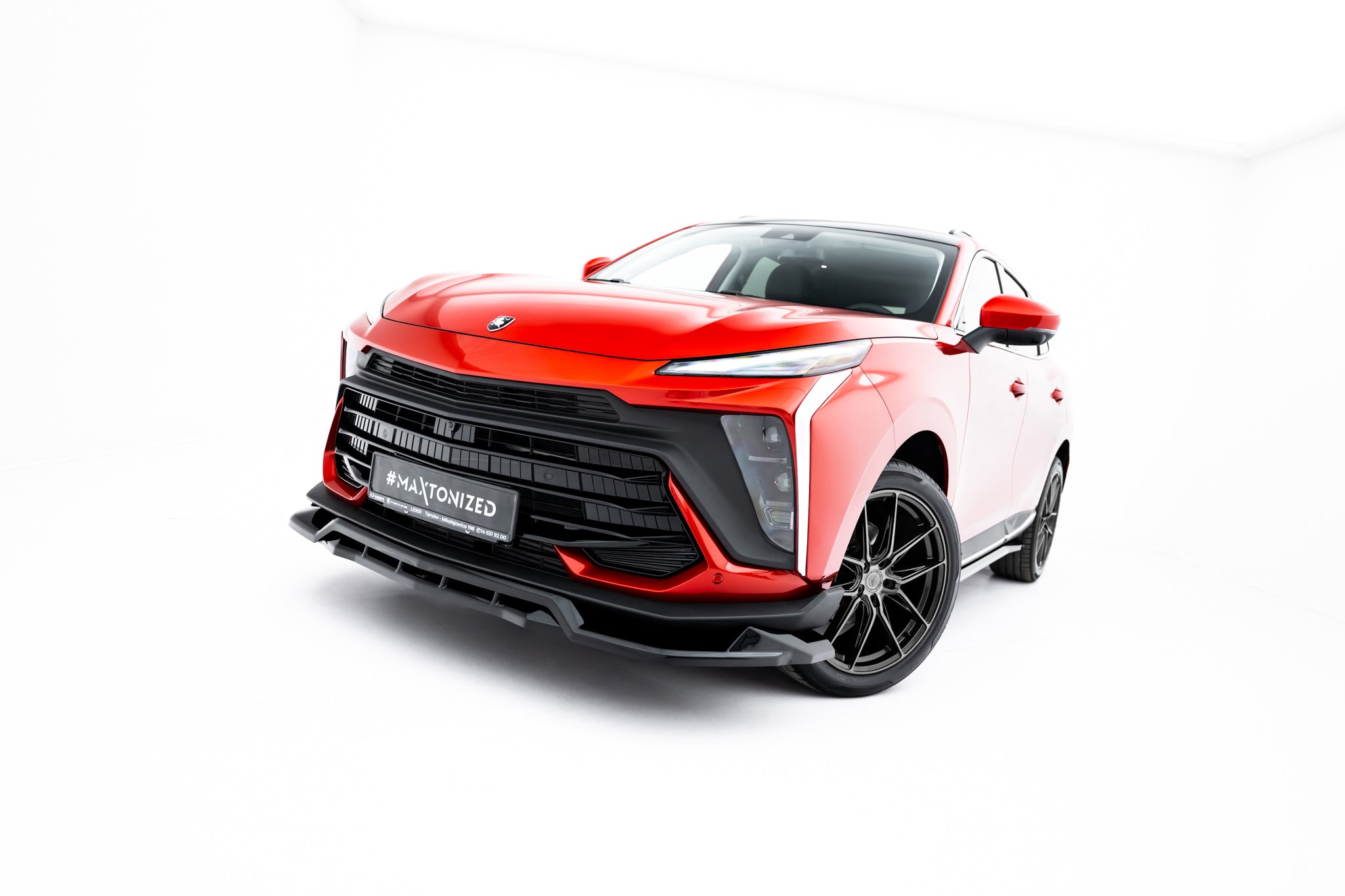 Frontspoiler på rød Forthing T-Five MK1 SUV med sort grill, LED-lys og sorte alufelger i fotostudio.