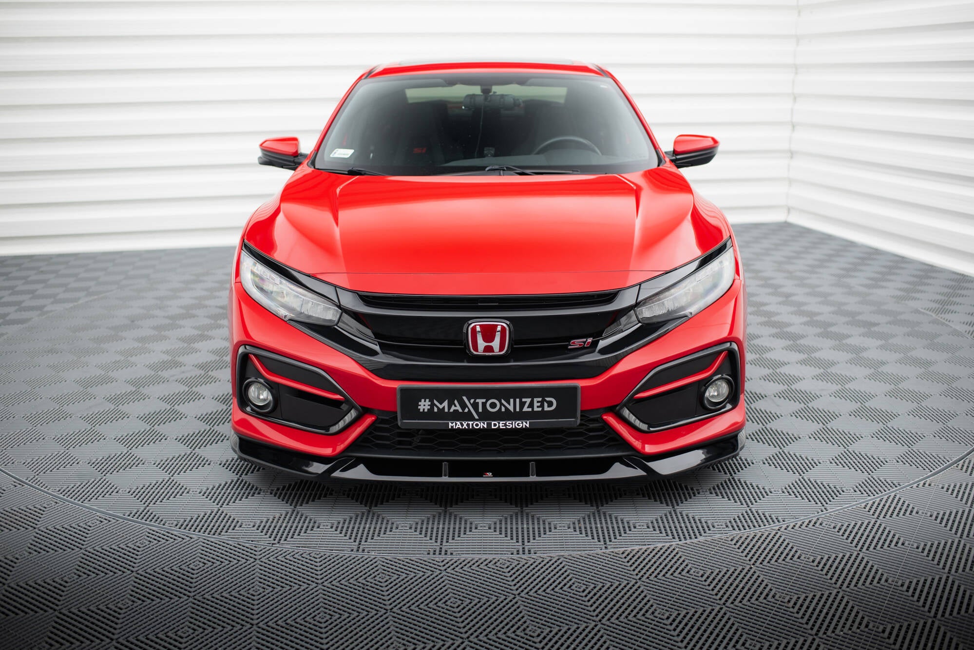 Frontleppe på rød Honda Civic Si MK10 sett forfra med svarte detaljer og skilt, fotografert innendørs.