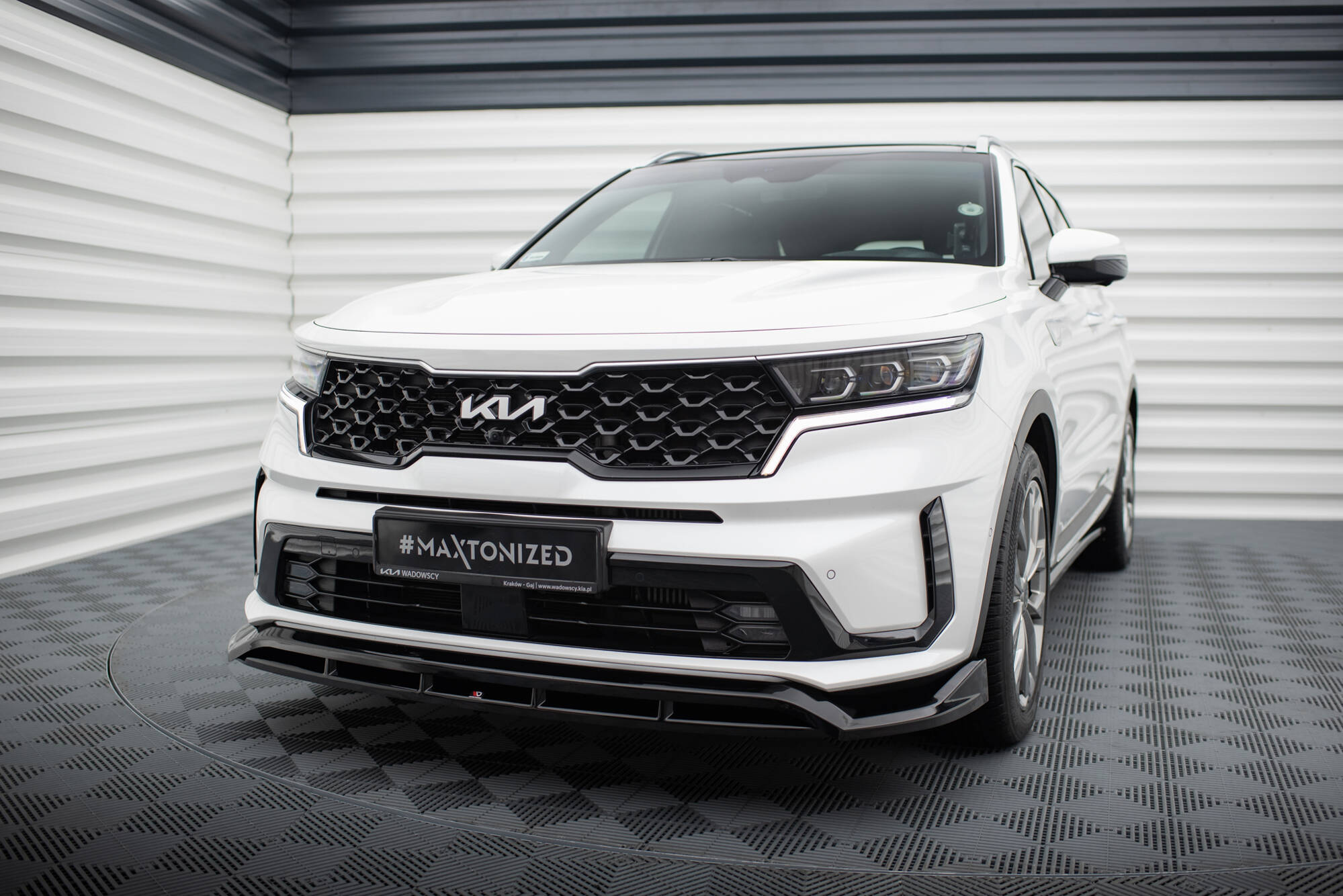 Frontspoiler på Kia Sorento MK4 hvit SUV med sort grill, LED-lys og kromdetaljer innendørs.