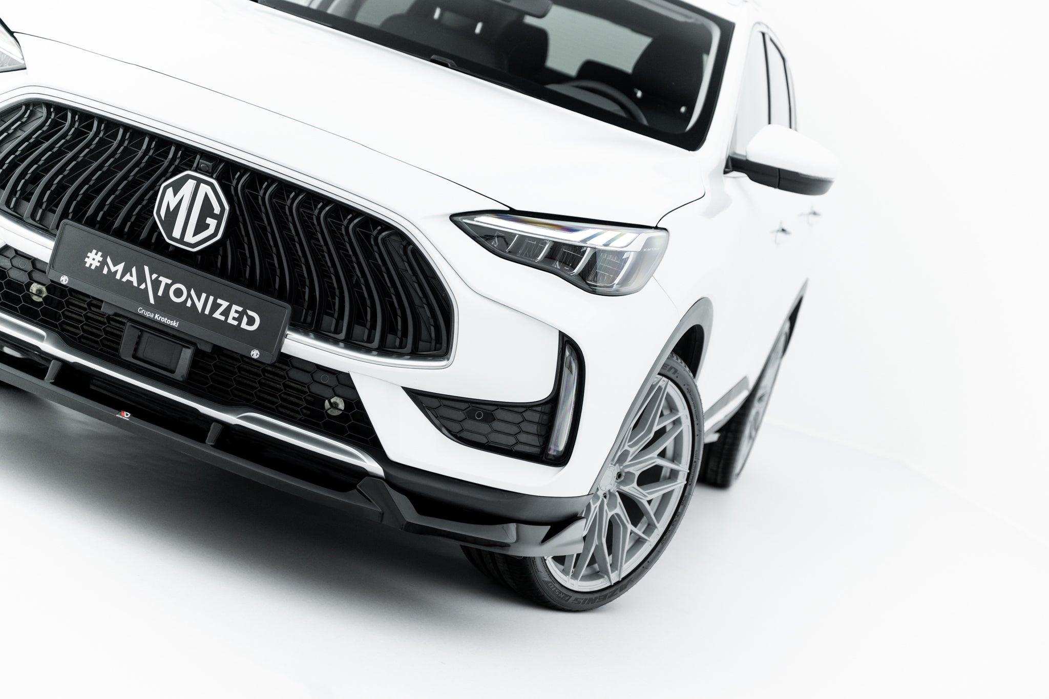 Spoiler til MG HS MK1 Facelift på hvit bil med sort grill, LED-frontlys og sportslige detaljer.