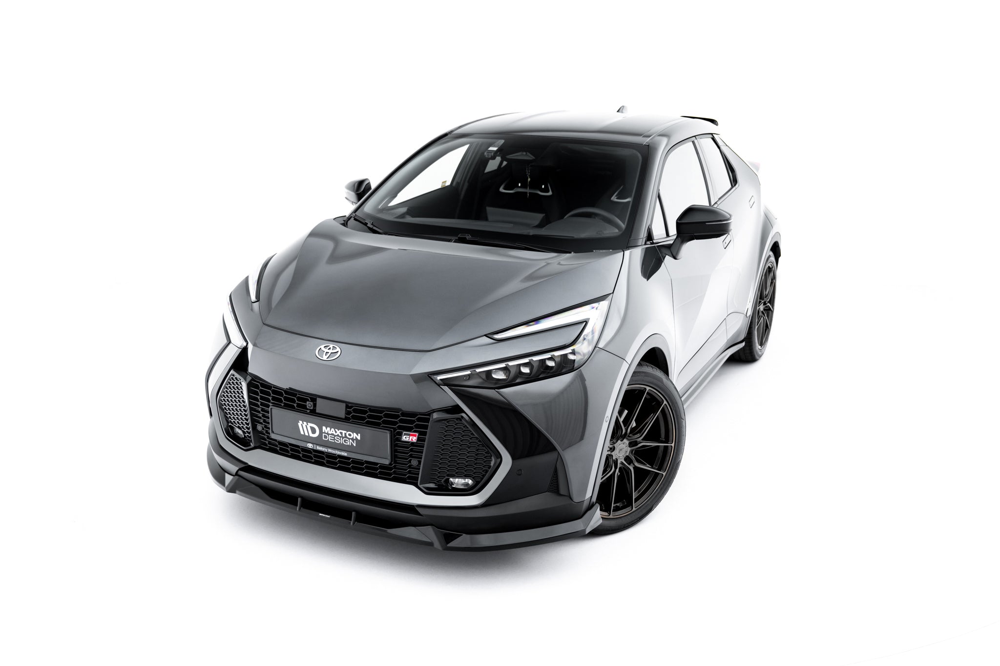 Frontspoiler Toyota C-Hr MK2 med sportslig design på grå bil, sorte felger og markante frontlys.