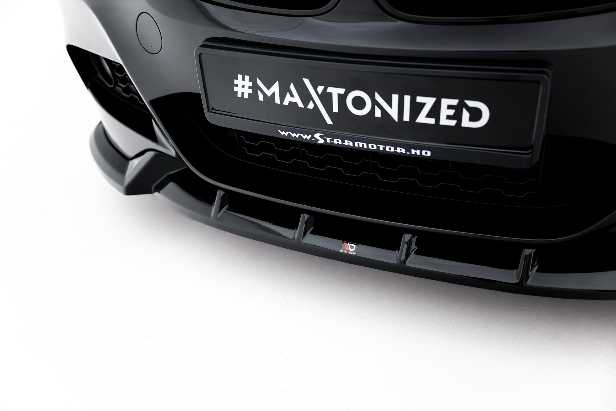 Spoiler til BMW 3 GT F34 M-Pakke V.1, sort plast med logo, nærbilde forfra mot lys bakgrunn.