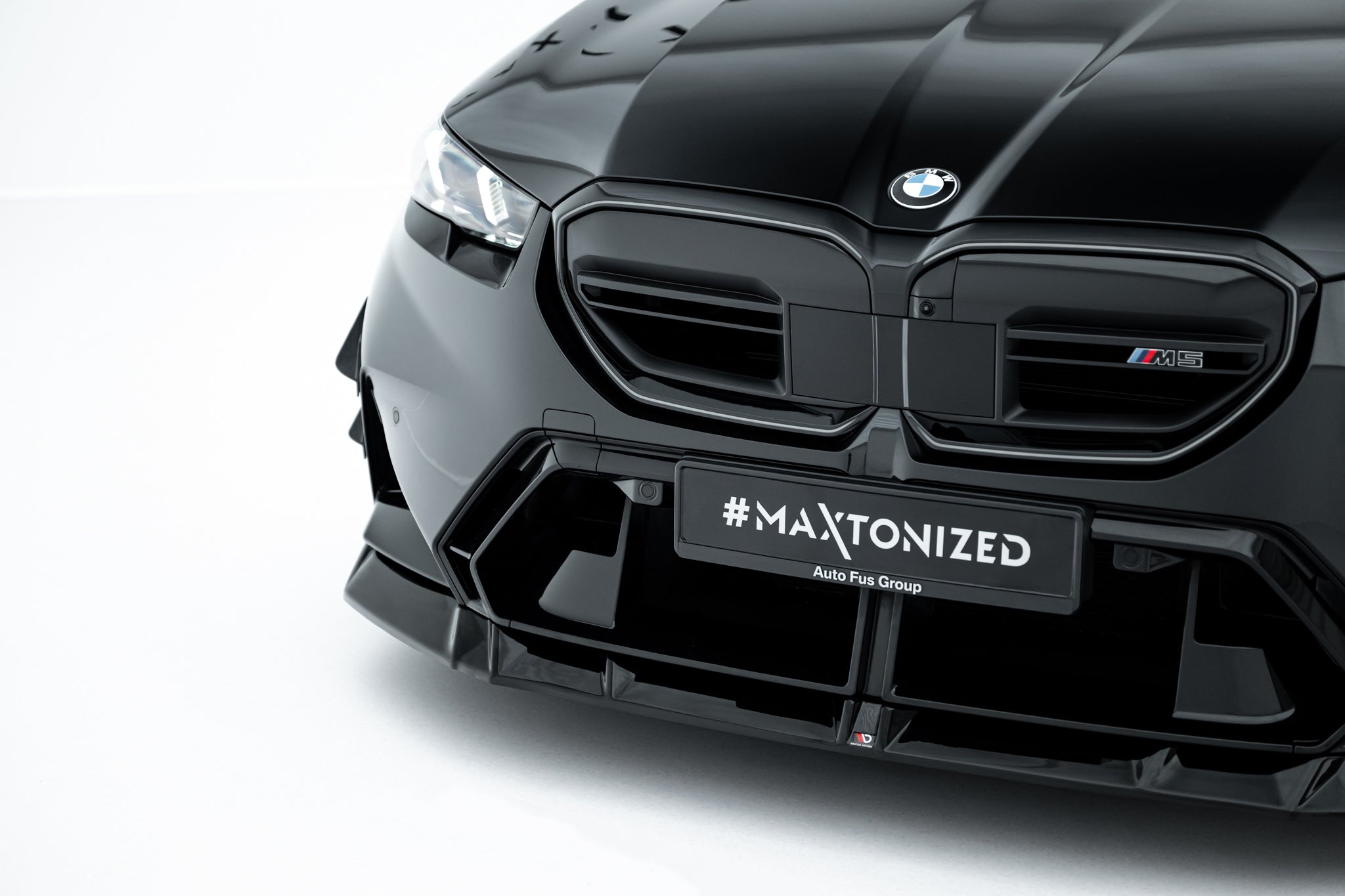 Frontspoiler BMW M5 G90 i sort høyglans med markant grill, sportslig støtfanger og M5-emblem.