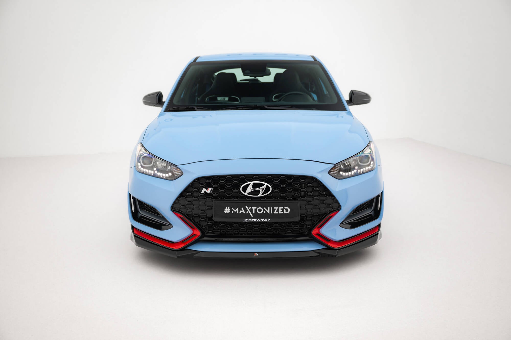 Frontleppe på Hyundai Veloster N MK2 V.1 med svarte og røde detaljer, sett forfra i lyst rom.