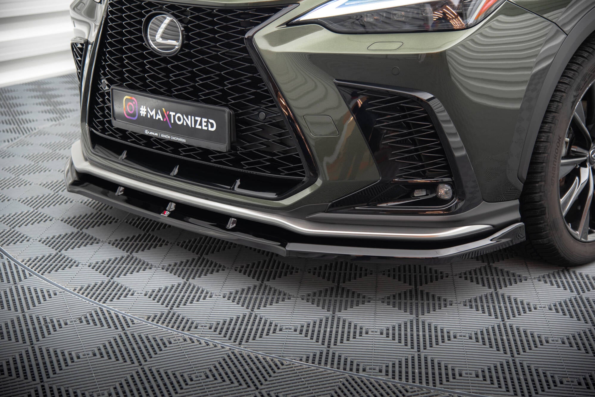 Frontspoiler Lexus Nx F-Sport MK2 V.1 i sort blank finish med markerte linjer på mørkgrønn bil.