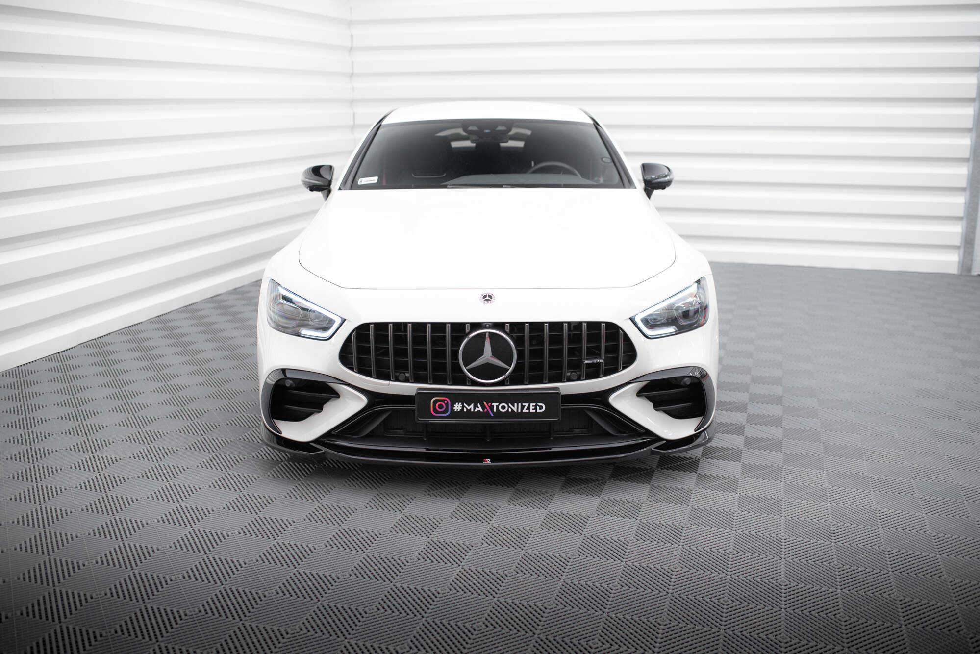 Frontleppe Mercedes GT 43 4 Dør Coupe med sort grill, LED-lykter og sporty detaljer, sett rett forfra.