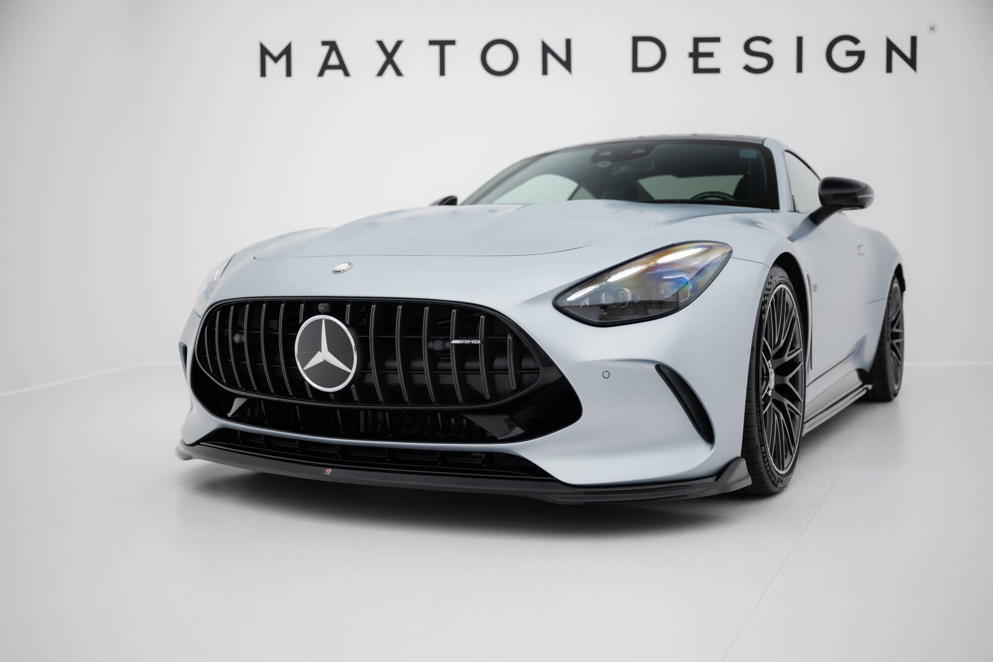 Frontspoiler Mercedes GT 63 vises forfra med svart grill, store felger og aerodynamisk design på lyst underlag.