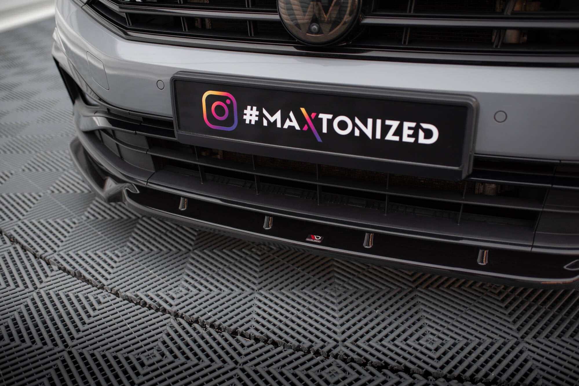 Spoiler til VW Passat B8 R-Line Facelift V.1, sort frontsplitter montert under grå støtfanger.