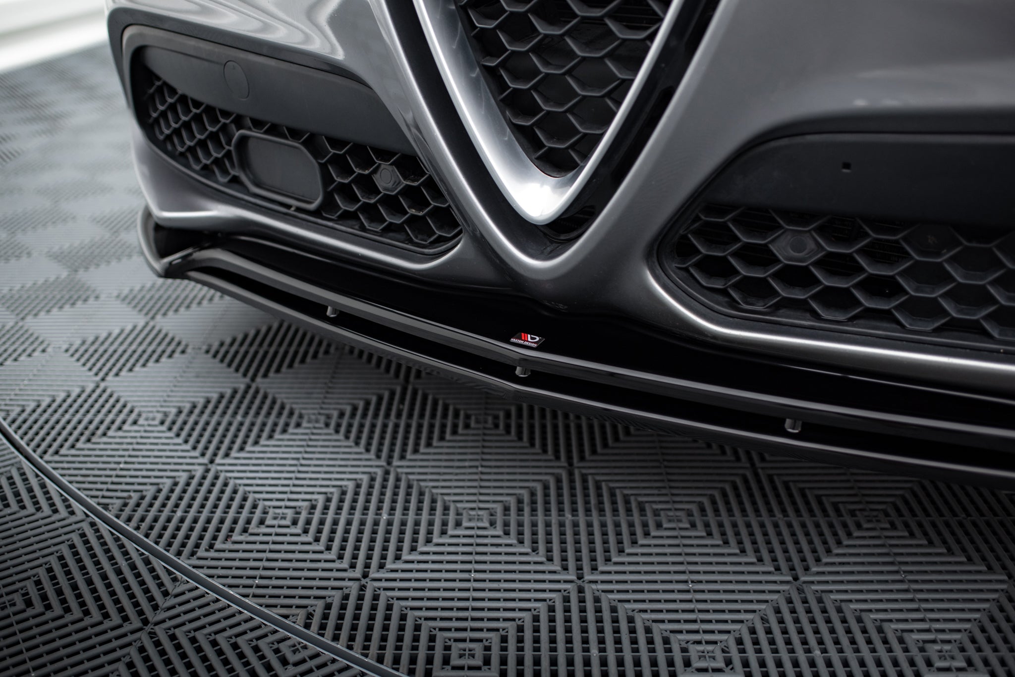 Spoiler til Alfa Romeo Stelvio MK1 V.2 i grått med sort grill, kromdetaljer og aerodynamisk frontsplitter.