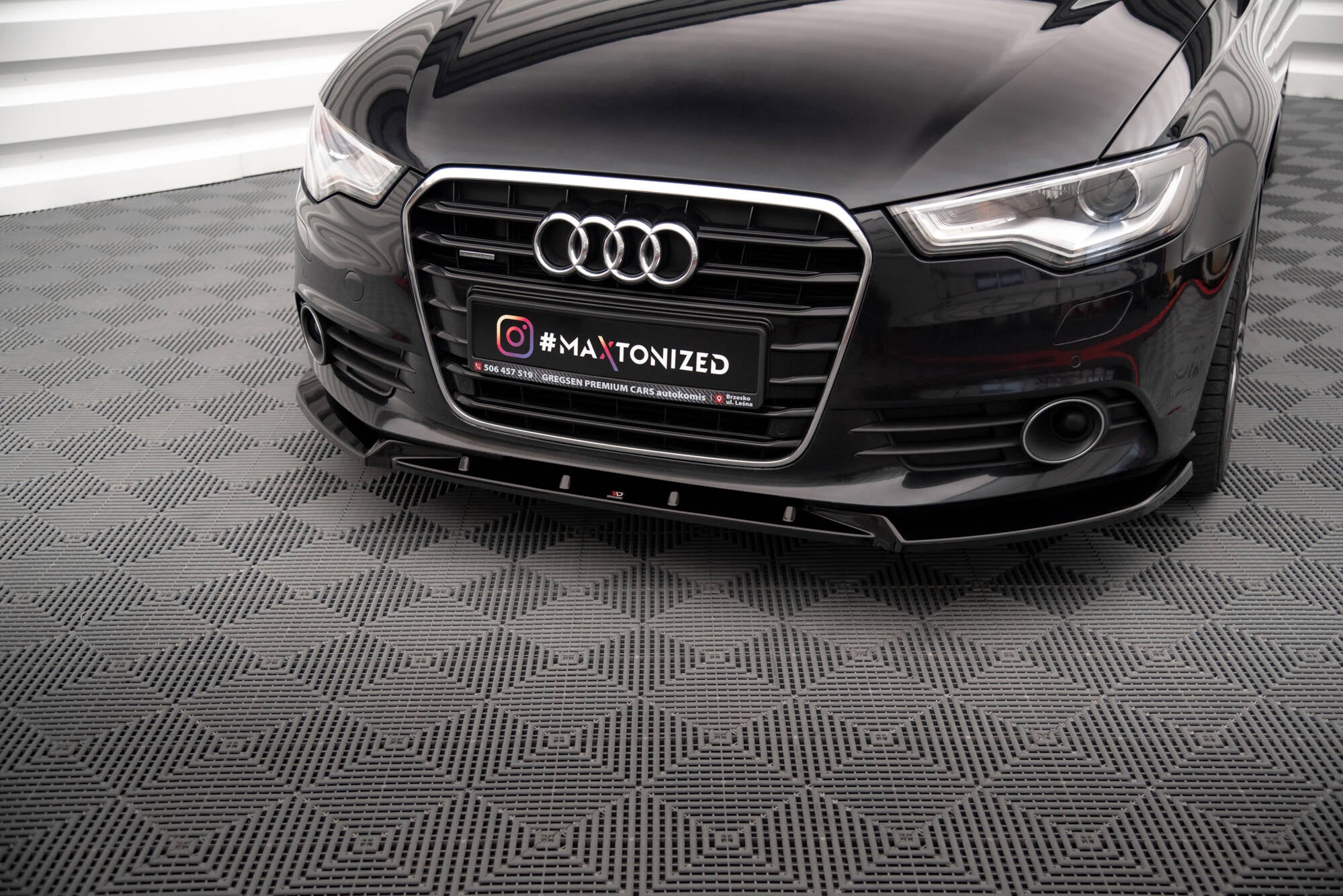 Frontspoiler Audi A6 C7 V.2 montert under sort bilfront med kromdetaljer og markant grill.