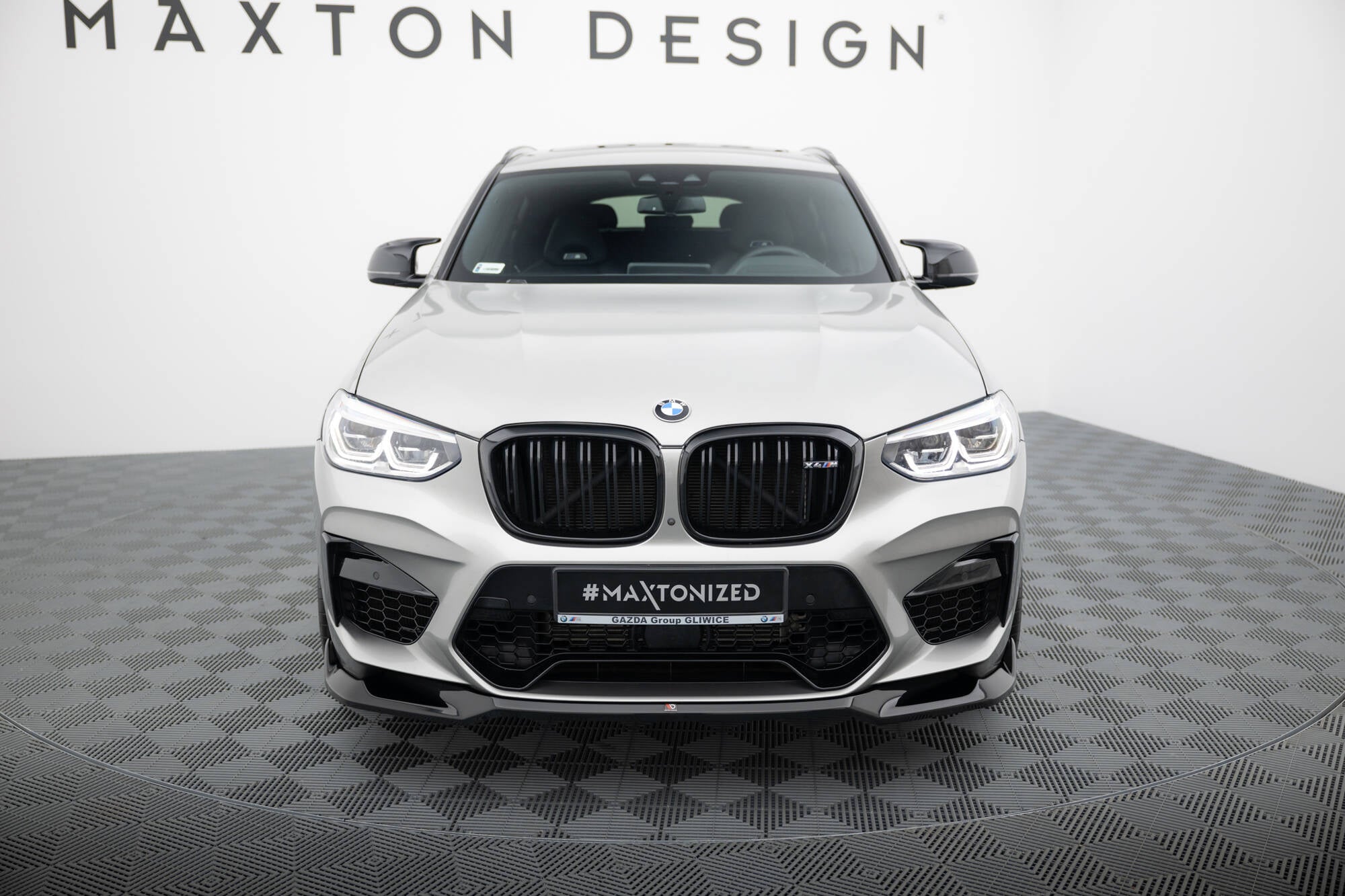 Frontleppe på BMW X4 M F98 V.2, hvit SUV forfra med sorte detaljer og Maxton Design-logo.
