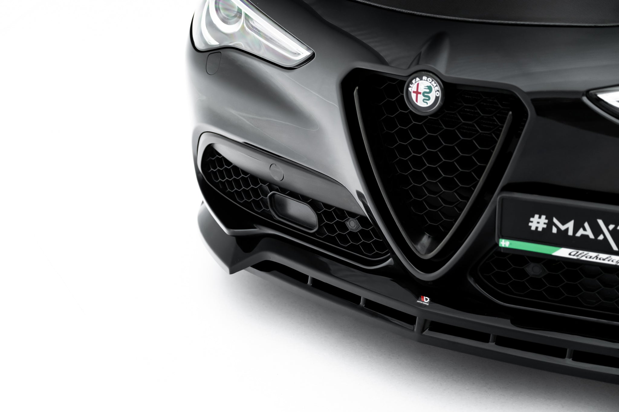 Spoiler på Alfa Romeo Stelvio MK1 V.3 med sort bikubemønstret grill og tydelig merke foran.