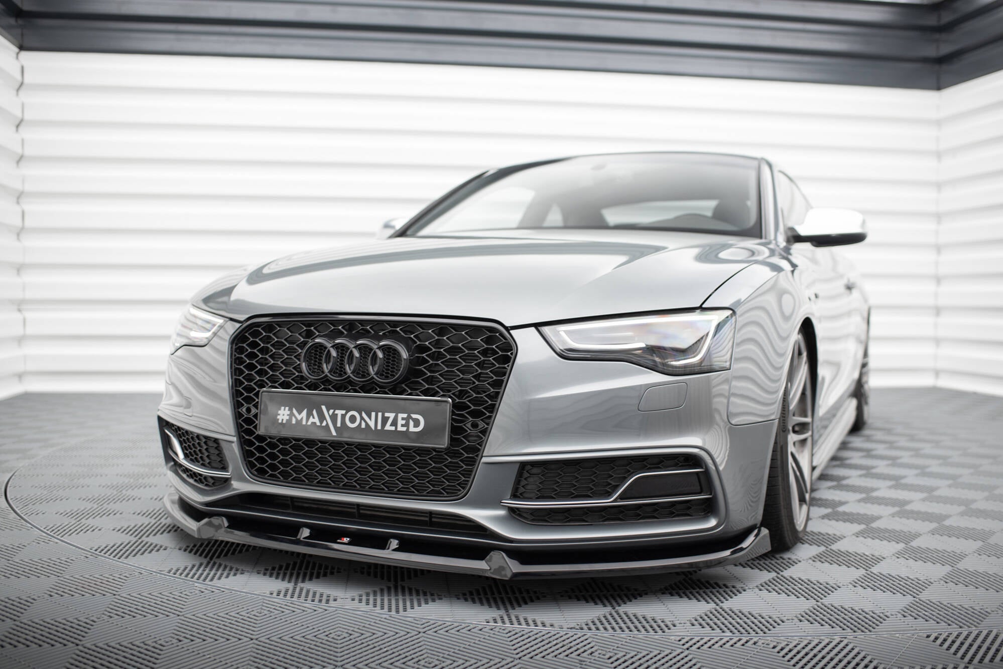 Frontspoiler Audi S5 S-Line Coupe med svart grill og lav frontlepe i lyst showroom med rutet gulv.