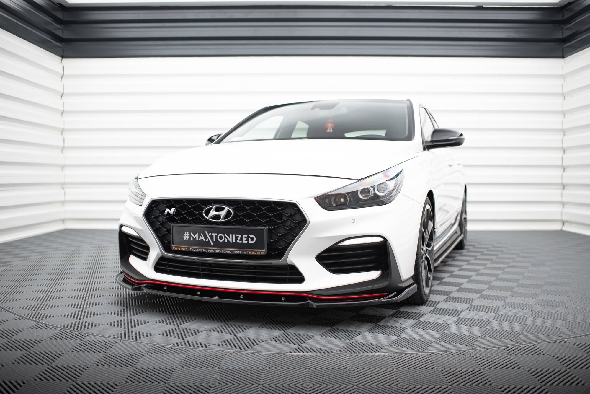 Frontspoiler Hyundai I30 N MK3 Hatchback med røde detaljer og sort grill sett forfra i lyst rom.