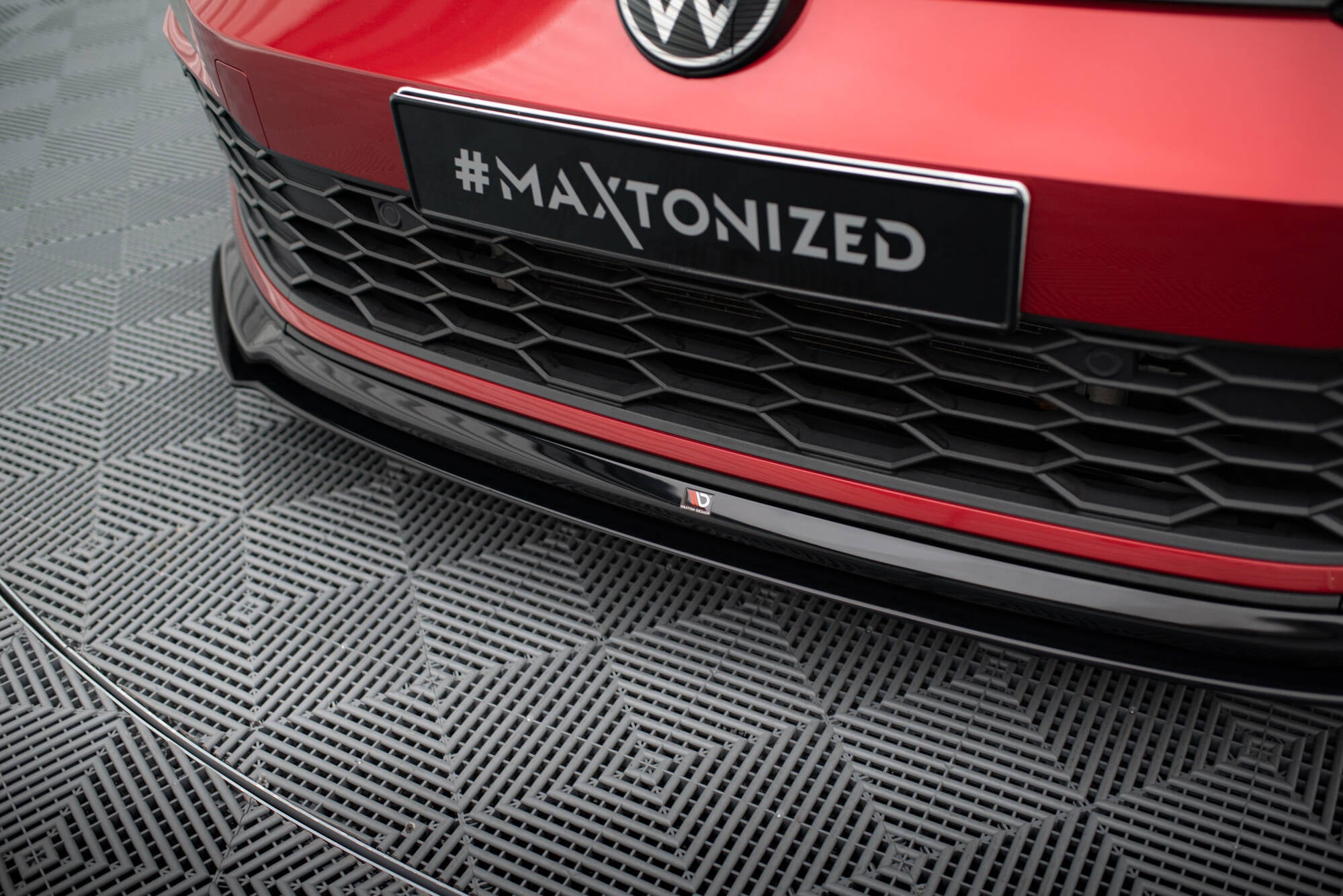 Spoiler til VW Golf MK8 GTI i svart blank plast montert under rød støtfanger med honeycomb-grill.