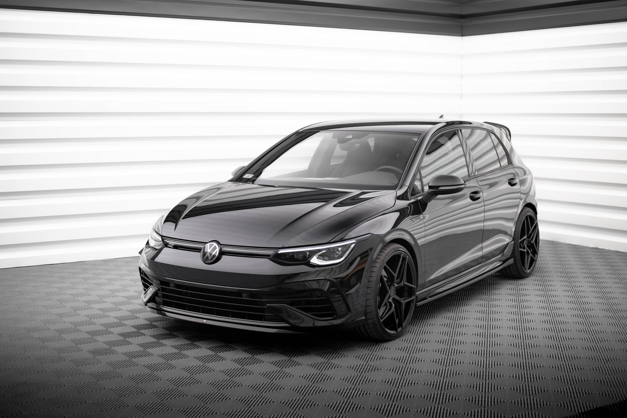 Spoiler på sort VW Golf R MK8 V.7 sett i trekvart forfra med blank lakk og mørke felger.