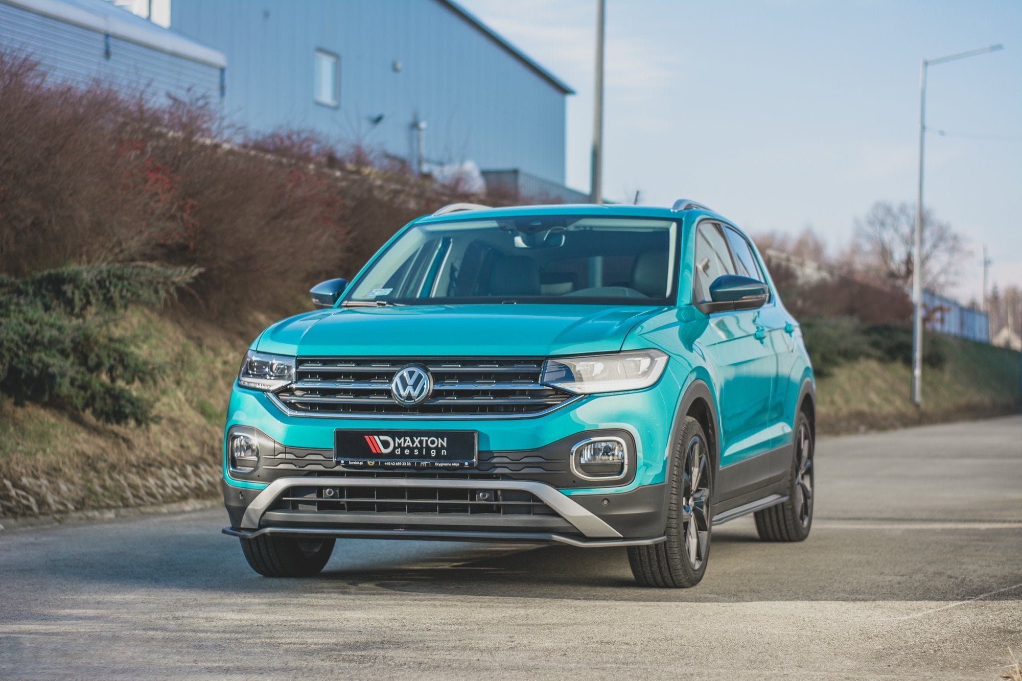 Frontleppe på turkisblå VW T-Cross SUV med svarte og sølv detaljer, parkert på asfaltvei.