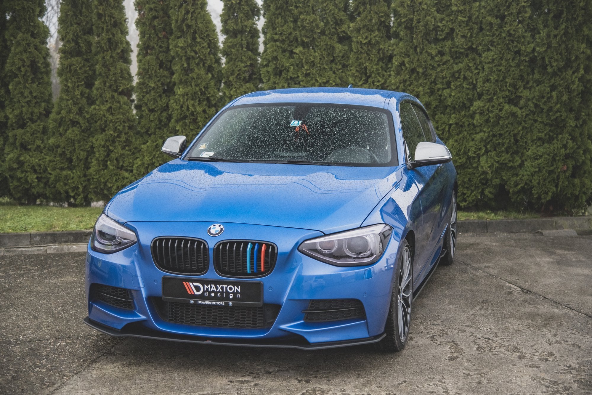 Frontleppe på BMW M135I F20 2011-2015 sett forfra med svarte grilldetaljer og regndråper.