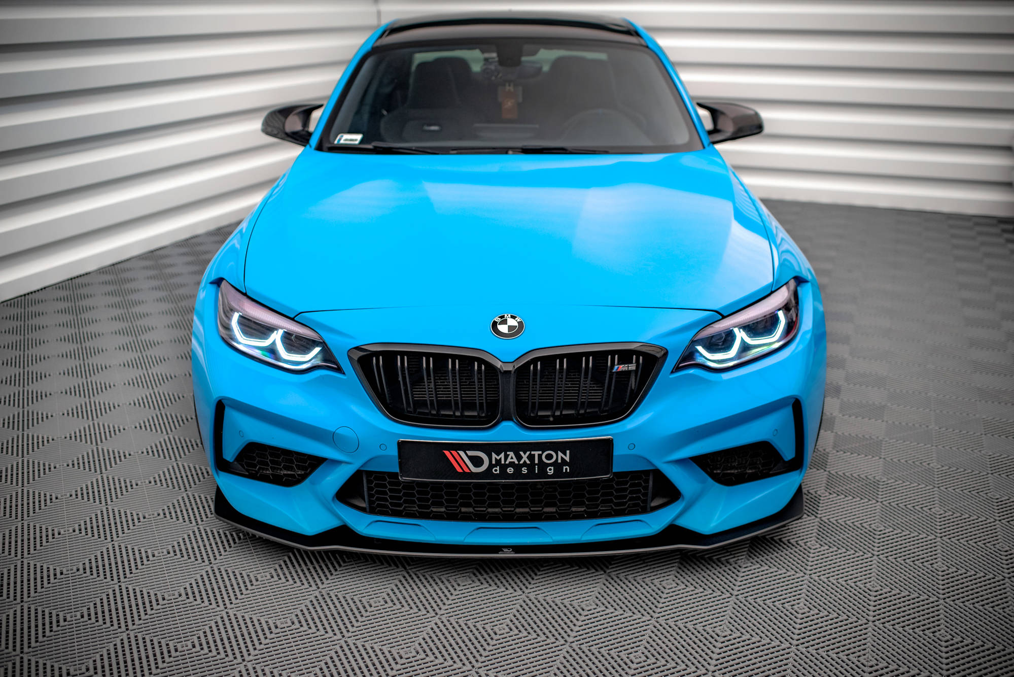 Frontspoiler BMW M2 Competition F87 i blått sett forfra med sorte detaljer og LED-lys.